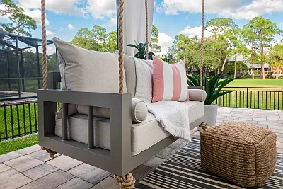 Connie swing bed in gray with ivory cushions, blush striped pillows, and a woven jute pouf