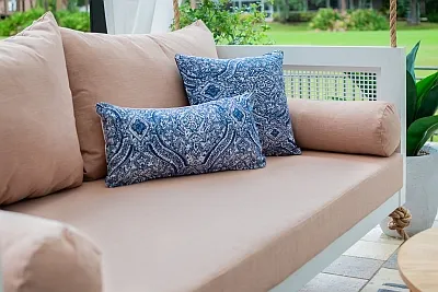 Close-up of blush Sunbrella cushions with blue medallion print pillows on the Debbie swing bed
