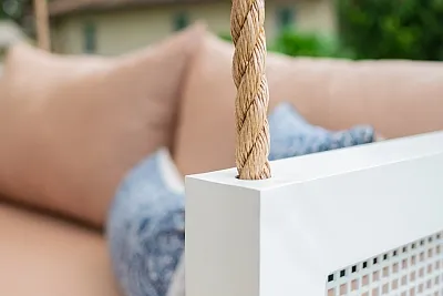 Detail of manila rope threaded through the white perforated frame corner of the Debbie swing bed