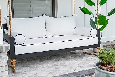 Maggie swing bed in black with white Sunbrella cushions and bolster pillows on a covered porch