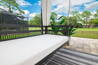 Shirley swing bed white mattress cushion and bronze frame overlooking a lawn