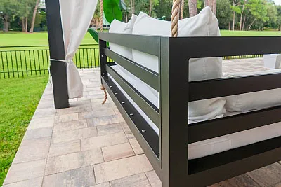 Close-up of the Shirley swing bed horizontal slat frame in bronze with white cushions