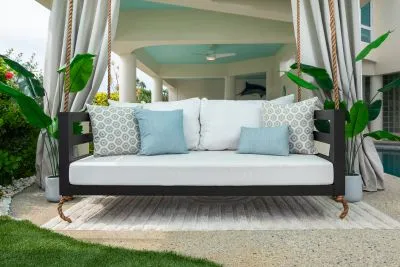 Maggie swing bed in black with white cushions and aqua and gray patterned pillows under a poolside cabana