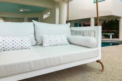 Close-up of the white Debbie swing bed with ivory cushions and aqua diamond print pillows