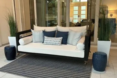 Shirley swing bed in black with white cushions, navy pillows, and matching navy garden stools