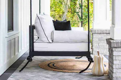 Sophia swing bed in black with white cushions and fall decor on a round jute rug