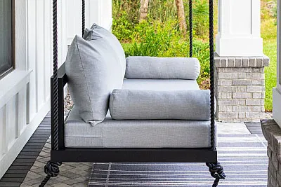 Sophia swing bed in black with gray cushions and bolster pillows on a striped outdoor rug
